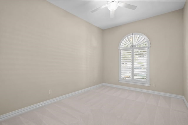 spare room with light carpet, ceiling fan, and baseboards