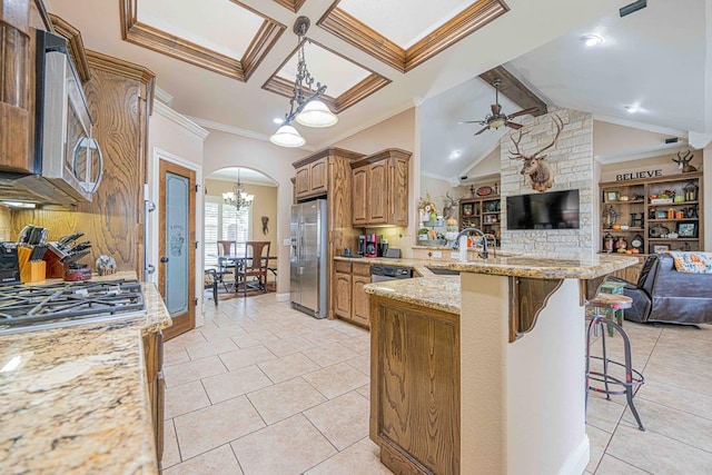 kitchen with a breakfast bar, ceiling fan with notable chandelier, crown molding, hanging light fixtures, and stainless steel appliances