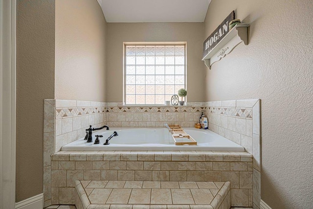 bathroom featuring tiled tub and vaulted ceiling