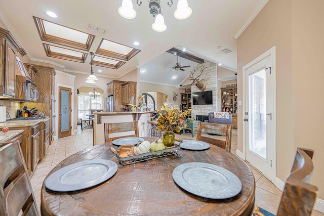 dining area featuring a fireplace, ornamental molding, coffered ceiling, ceiling fan with notable chandelier, and beamed ceiling