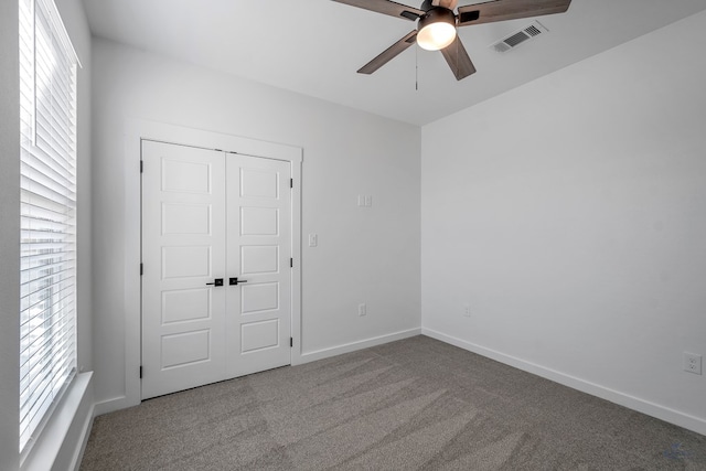 unfurnished bedroom with ceiling fan, visible vents, baseboards, a closet, and carpet