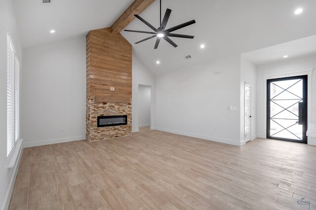 unfurnished living room with a fireplace, visible vents, light wood-style floors, high vaulted ceiling, and beamed ceiling