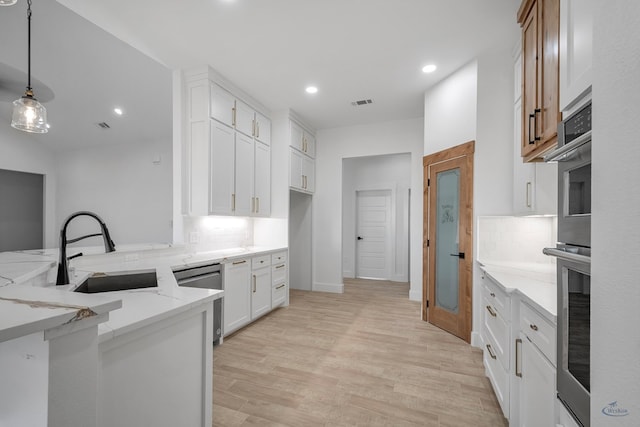 kitchen featuring sink, white cabinetry, light stone counters, decorative light fixtures, and appliances with stainless steel finishes