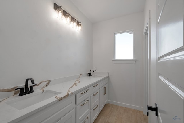 bathroom featuring double vanity, a sink, baseboards, and wood finished floors