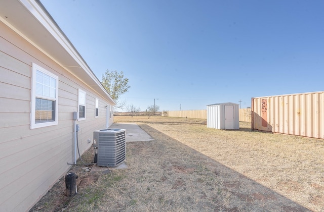 view of yard featuring an outbuilding, fence, central AC, and a shed