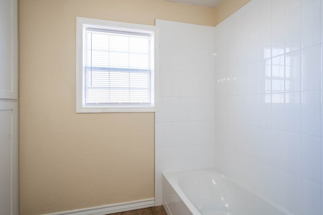 bathroom with a textured wall and baseboards