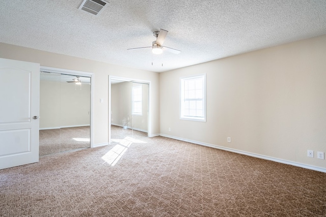 unfurnished bedroom with visible vents, multiple closets, baseboards, and carpet flooring