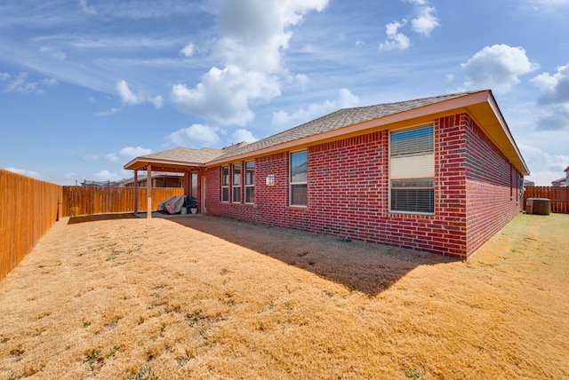 view of property exterior with central AC, brick siding, and a fenced backyard