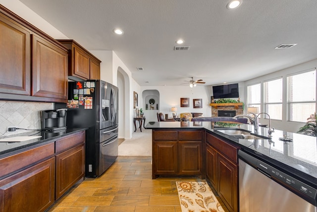 kitchen with appliances with stainless steel finishes, visible vents, a sink, and a stone fireplace