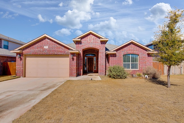 view of front of home with a garage, driveway, brick siding, and fence