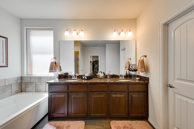 bathroom featuring wood finished floors, double vanity, a sink, and a bath