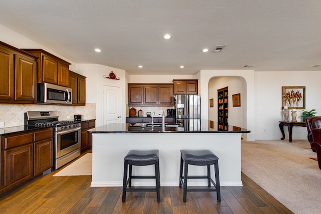 kitchen featuring appliances with stainless steel finishes, decorative backsplash, a sink, and a kitchen breakfast bar