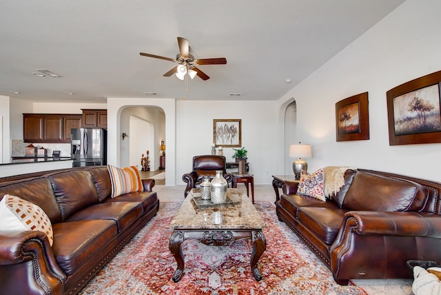 living room featuring arched walkways, visible vents, light carpet, and a ceiling fan