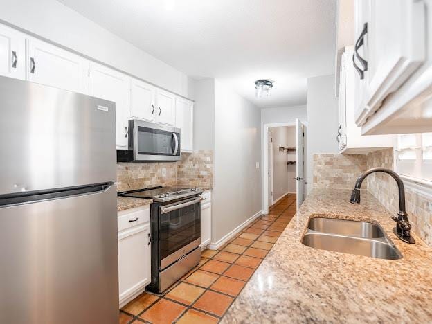 10807 E County Rd 104, Midland, TX 79706 - kitchen with stainless steel appliances, backsplash, white cabinetry, and light tile patterned floors
