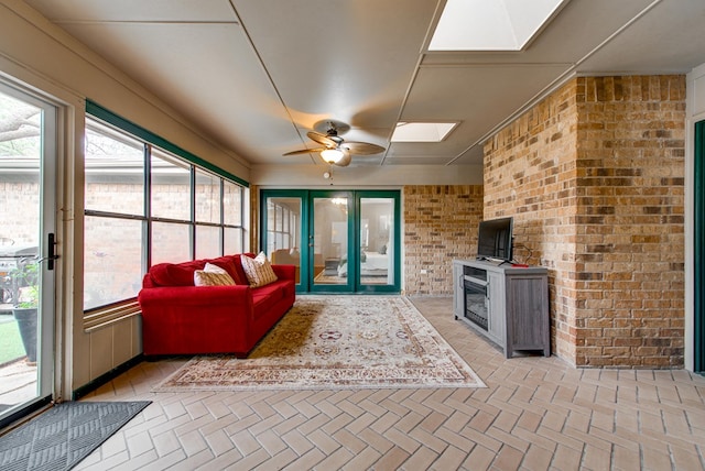 sunroom with a skylight, brick floor, french doors, and brick wall