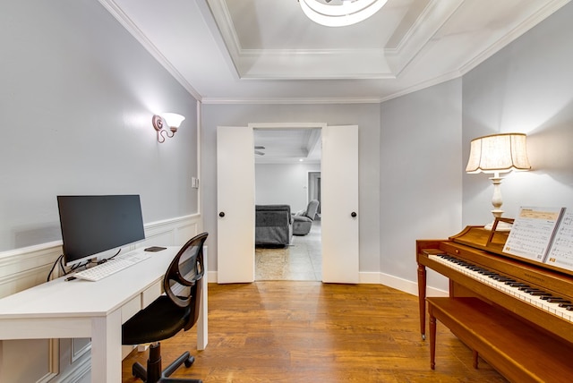 office with crown molding, wainscoting, wood finished floors, and a raised ceiling