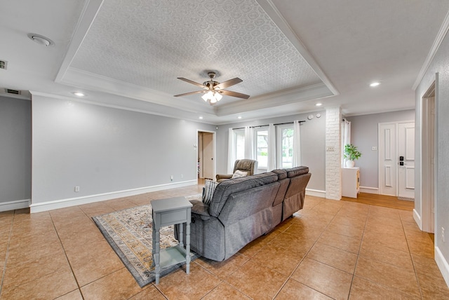 living room with visible vents, a raised ceiling, light tile patterned flooring, ornamental molding, and a ceiling fan
