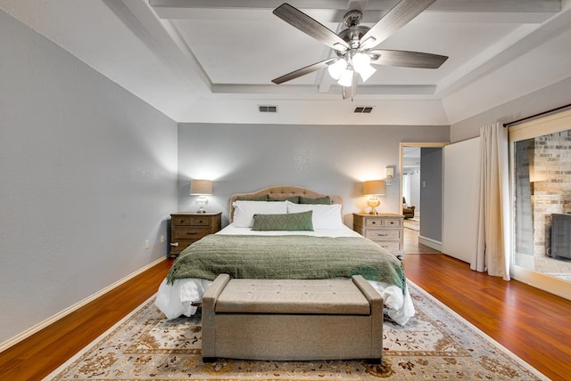 bedroom with visible vents, a raised ceiling, and wood finished floors