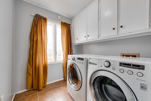 laundry room with light tile patterned floors, washing machine and clothes dryer, cabinet space, and baseboards