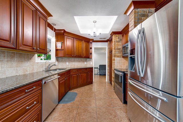 kitchen featuring an inviting chandelier, dark stone counters, decorative backsplash, appliances with stainless steel finishes, and a sink