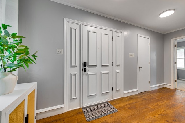 foyer entrance featuring baseboards, wood finished floors, and crown molding