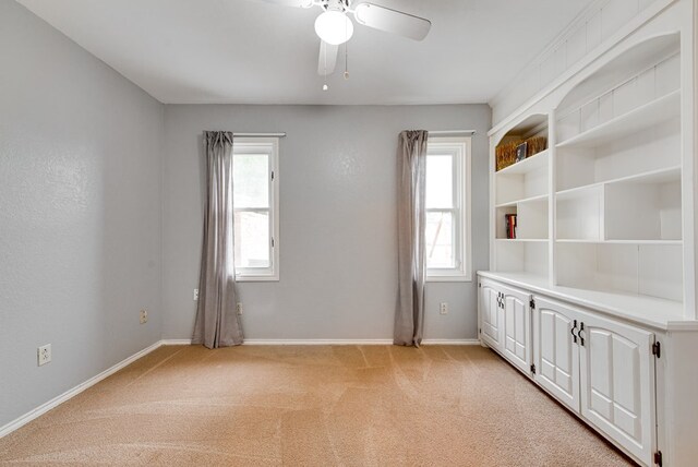 spare room with baseboards, light carpet, and ceiling fan