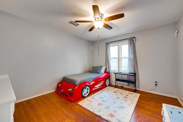 bedroom with visible vents, ceiling fan, wood finished floors, and baseboards