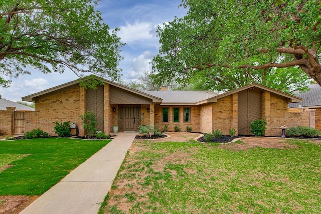 mid-century modern home with a front lawn, fence, a chimney, and brick siding