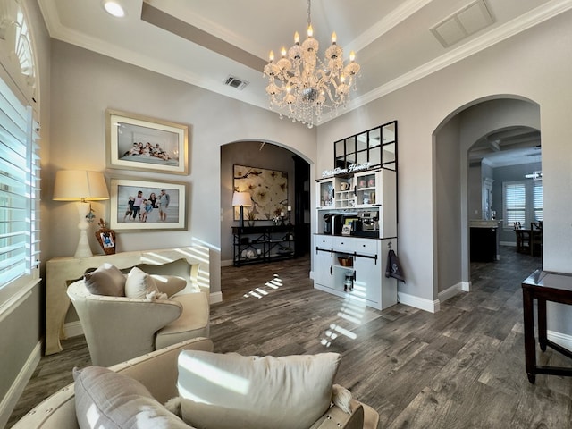 living room with dark hardwood / wood-style flooring, crown molding, a chandelier, and a raised ceiling