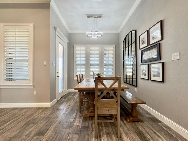 dining space with dark wood-type flooring, crown molding, and a notable chandelier