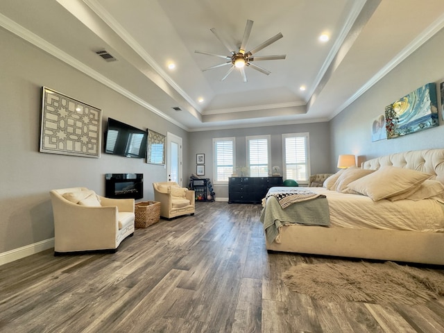 bedroom with ceiling fan, a tray ceiling, dark hardwood / wood-style floors, and ornamental molding