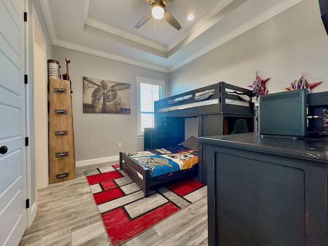 bedroom featuring ceiling fan, light wood-type flooring, crown molding, and a tray ceiling