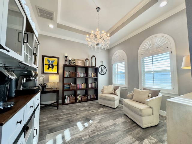 sitting room featuring a tray ceiling, dark hardwood / wood-style flooring, ornamental molding, and a chandelier