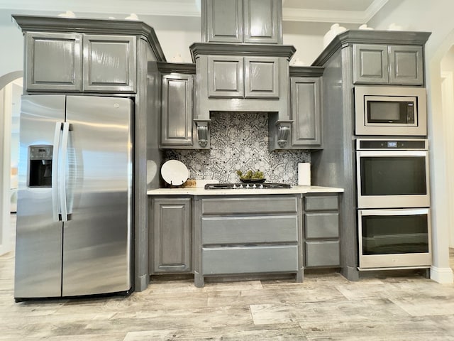 kitchen with tasteful backsplash, gray cabinets, crown molding, and stainless steel appliances