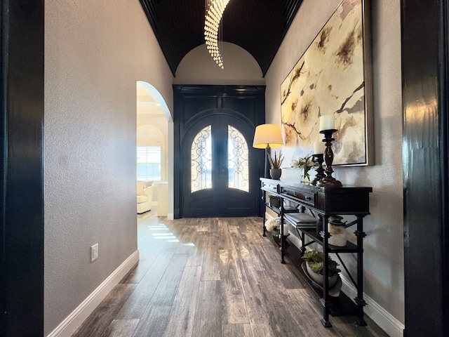 entrance foyer featuring wood-type flooring, brick ceiling, lofted ceiling, and french doors