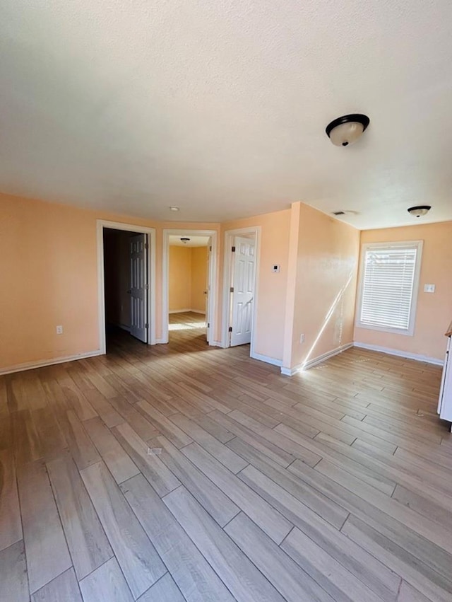 spare room with a textured ceiling and light wood-type flooring