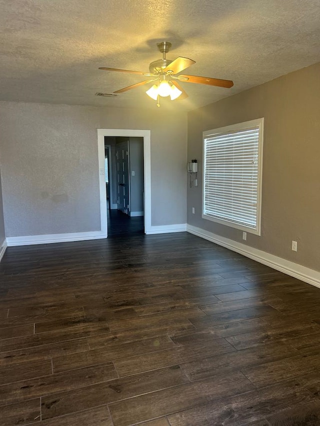 empty room with ceiling fan, dark hardwood / wood-style flooring, and a textured ceiling