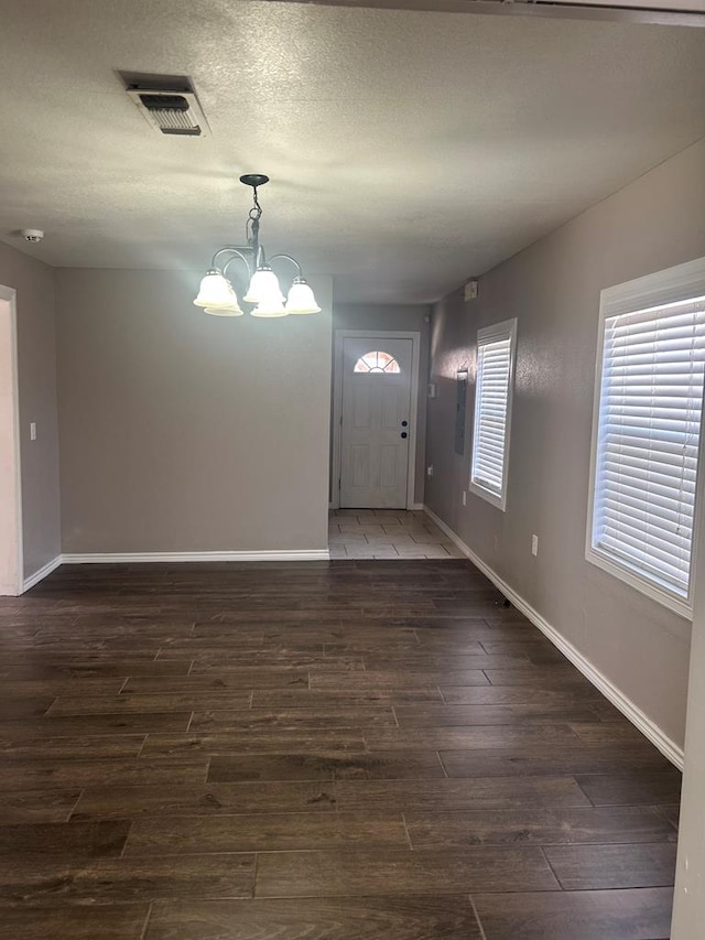 entryway with dark hardwood / wood-style floors, a notable chandelier, and a textured ceiling