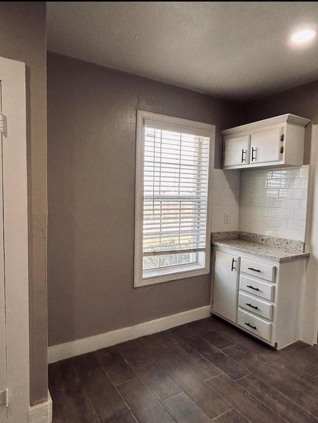 kitchen featuring tasteful backsplash, light stone counters, and white cabinets