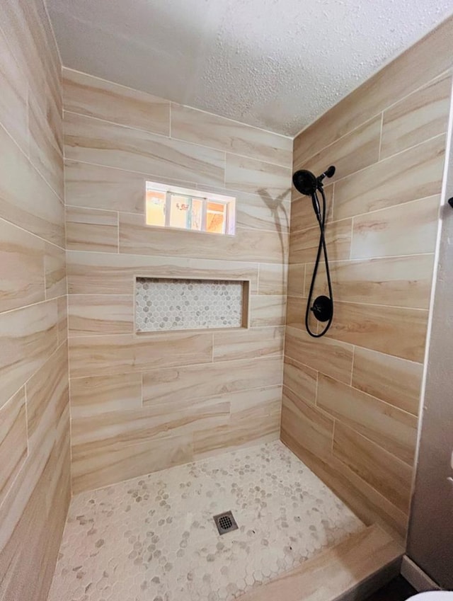 bathroom featuring a tile shower and a textured ceiling