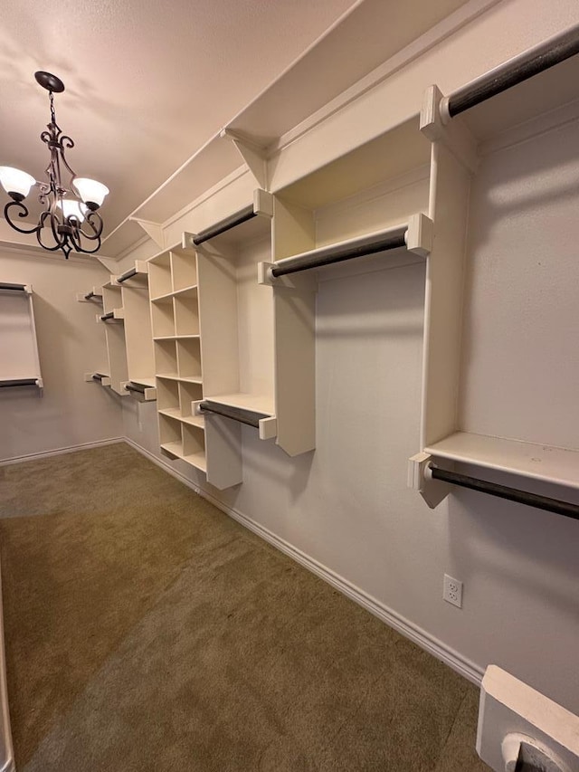 spacious closet featuring dark colored carpet and a notable chandelier