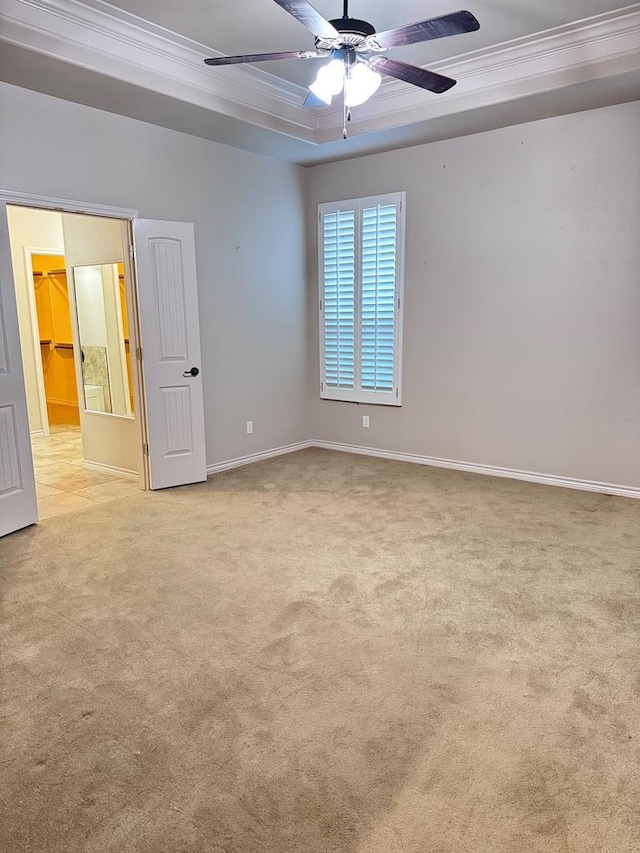 carpeted empty room featuring a tray ceiling, ceiling fan, and ornamental molding