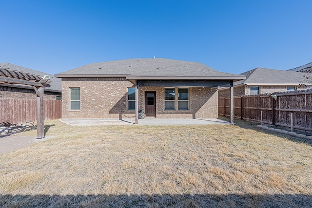 rear view of property featuring a yard, a fenced backyard, a patio, and brick siding