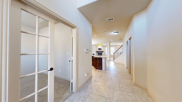 corridor with visible vents, light tile patterned flooring, stairway, and baseboards