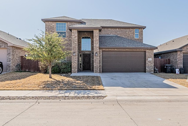 traditional-style home with a garage, brick siding, driveway, and fence