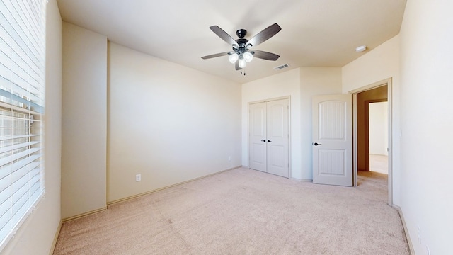 unfurnished bedroom with baseboards, visible vents, ceiling fan, carpet floors, and a closet