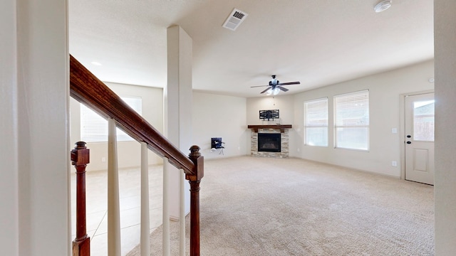 unfurnished living room with carpet floors, a fireplace, visible vents, a ceiling fan, and stairway