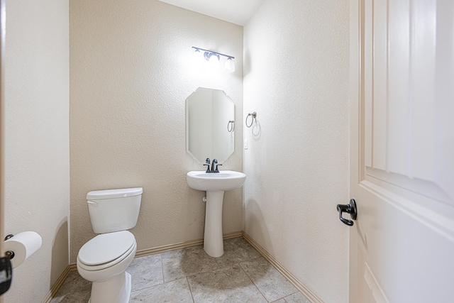 bathroom with toilet, baseboards, and tile patterned floors