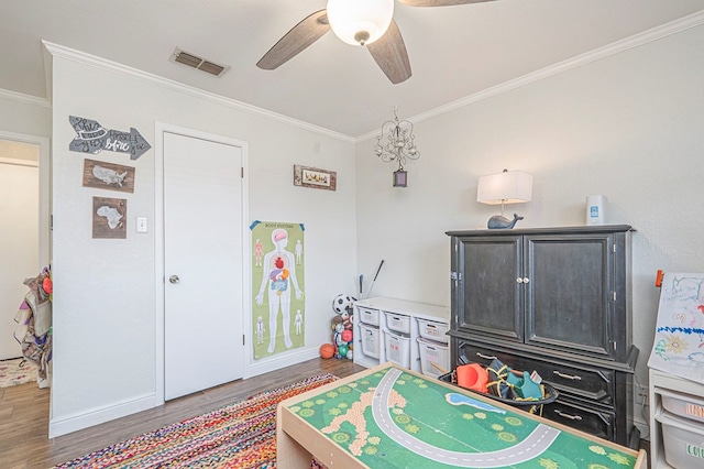 playroom featuring ceiling fan, visible vents, dark wood-style flooring, and ornamental molding