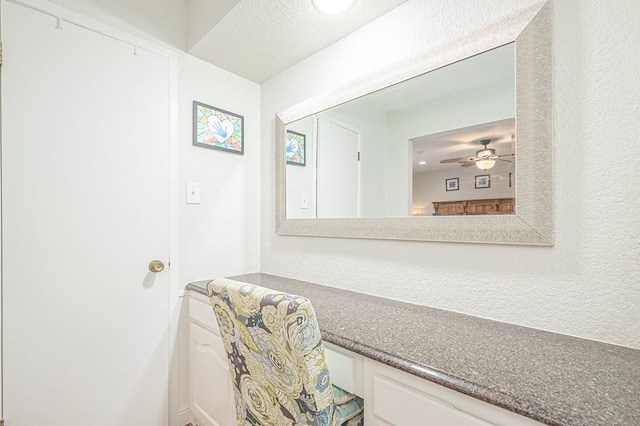 bathroom featuring ceiling fan and a textured wall